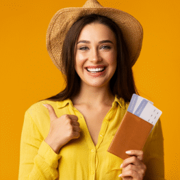 mujer-feliz-gesticulando-thumbsup-sosteniendo-boletos-y-pasaporte-fondo-amarillo